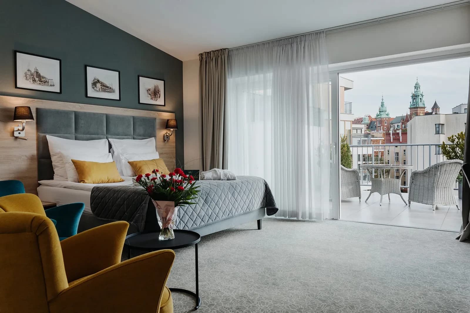 Bright bedroom with double bed, mustard pillows, balcony doors and distant city skyline view.